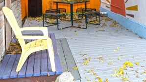 Un espace extérieur abrité, avec une table et des chaises, une clôture en bois et une fresque murale.