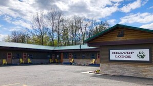 A motel named Hilltop Lodge with a parking lot, several rooms, and a signboard.