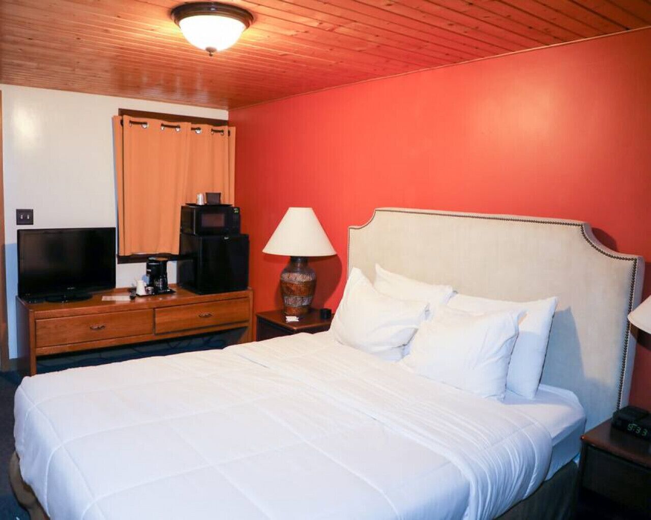 Ein Hotelzimmer mit Bett, Fernseher, Kaffeemaschine und Lampe.