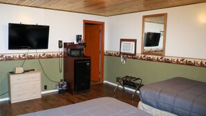 Une chambre comprenant un lit, une commode, une télévision, un four à micro-ondes et un réfrigérateur.