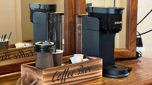 Una barra de café con una caja de madera que dice "Coffee Bar" y una máquina de café Keurig.