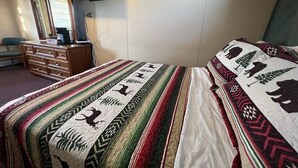 Habitación de hotel con cama, cómoda, televisor sobre un mueble y ventana.
