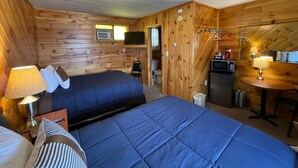 A wooden cabin room with two beds, a small kitchenette, and a dining area. - Lyons in Onaway - 2 Full Beds - Room 7 - Sleeps 4 (Onaway)