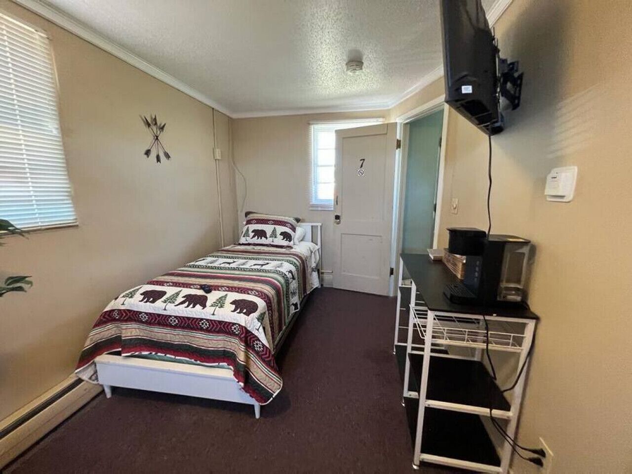 A small, cozy bedroom with a bed, a desk, and a television.