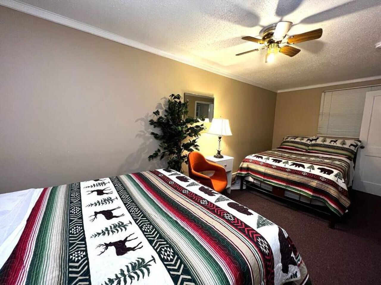 Habitación de hotel con dos camas, un ventilador de techo, una lámpara y una silla.