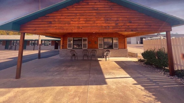 A building with a wooden exterior and a covered patio area with chairs. - Lyons in Onaway - 2 Full Beds - Room 2 - Sleeps 4 (Onaway)