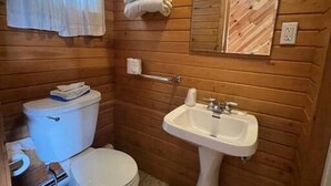 A compact bathroom with a toilet, sink, and a mirror.