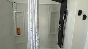 A bathroom with a bathtub, a shower curtain, and a towel rack. - The Western Roost | A Vensérra Retreat Near Hot Springs State Park (Thermopolis)