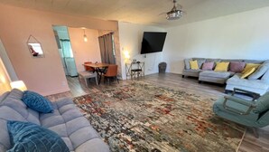 Un salon comprenant un canapé, un tapis à motifs, un téléviseur et un coin repas.
