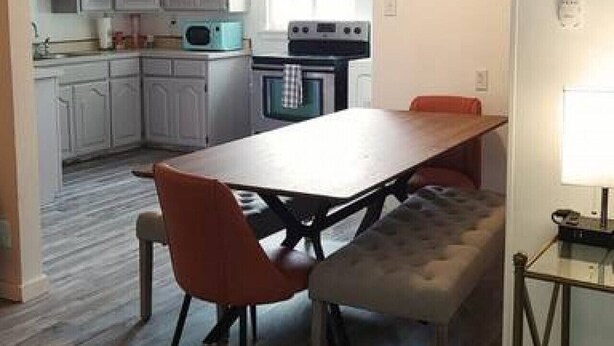 Une cuisine moderne avec des meubles blancs, un îlot central et un coin repas avec un banc.