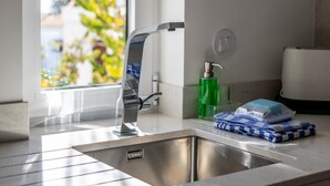A modern bathroom with a stainless steel sink, a faucet, a soap dispenser, and a towel dispenser.