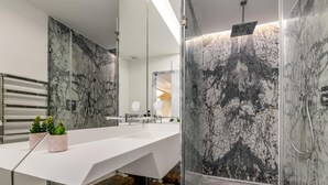 A modern bathroom with a marble vanity, a shower, and a bench.