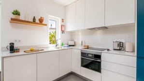 A modern kitchen with white cabinets, a built-in oven, and a window providing natural light.