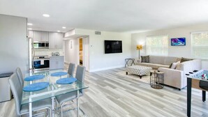 A modern apartment with a dining area, kitchen, living room, and a foosball table. - Beachside Retreat | Hot Tub | Fire Pit | WiFi (West Palm Beach)