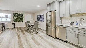 Eine moderne Küche mit Edelstahlgeräten, ein Essbereich mit Tisch und Stühlen sowie ein Wohnzimmer mit Sofa und Couchtisch.