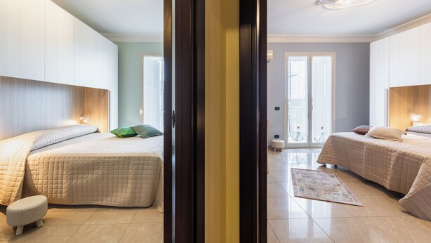 A modern bedroom with two beds, a large mirror, and a view of the city. - Casa Amica - Three Bedroom House, Sleeps 6 (Avola)