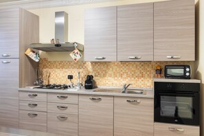 Una cocina moderna con armarios de madera, horno empotrado, microondas y cafetera.