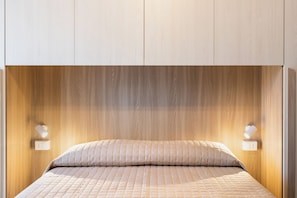 Ein Schlafzimmer mit einem hölzernen Kopfende, einem Bett mit gesteppter Bettdecke und zwei Wandleuchten.