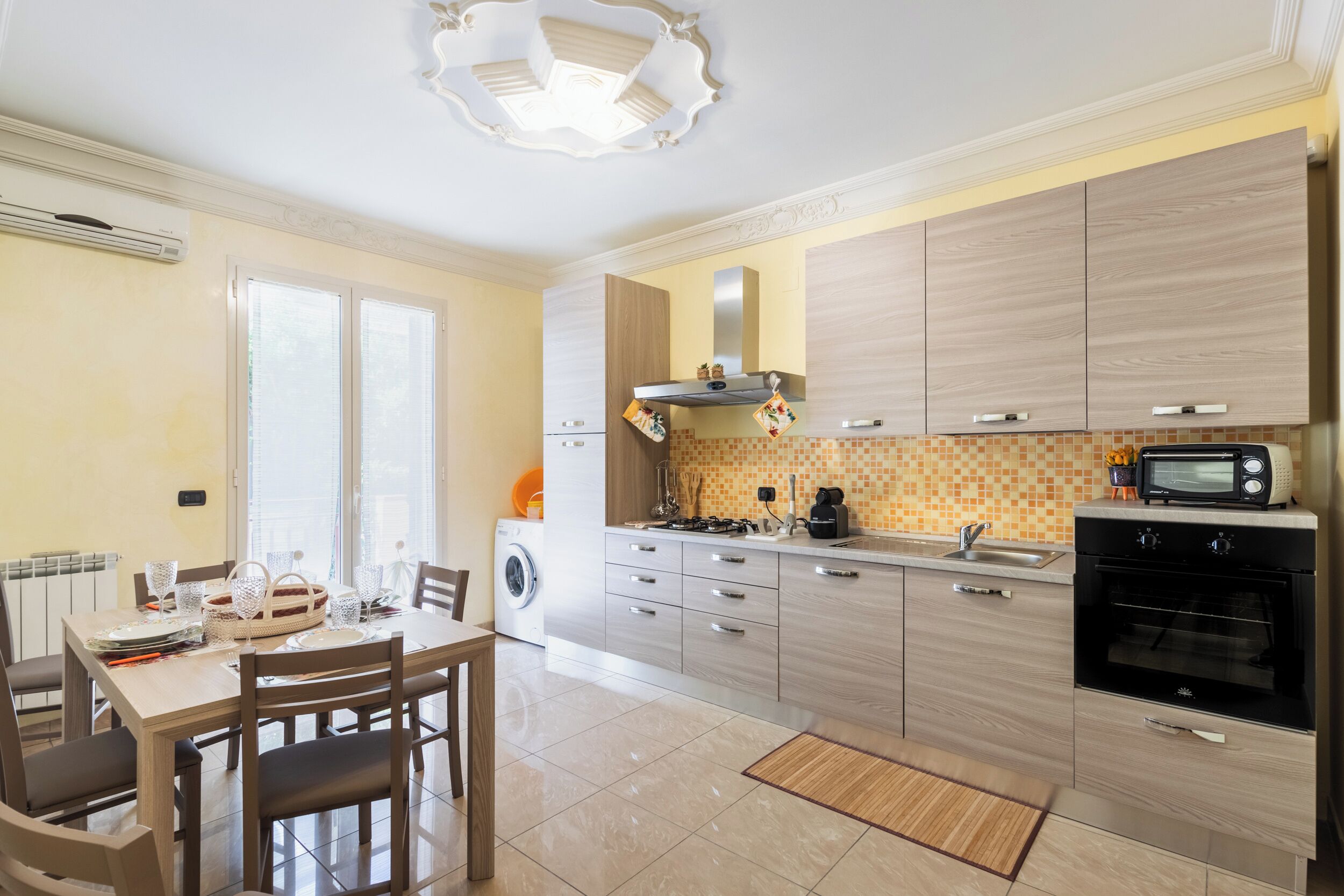 Una cucina moderna con zona pranzo, elettrodomestici integrati e un'ampia finestra.