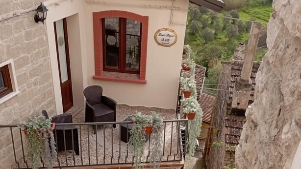 A two-story building with a balcony, stone walls, and a view of a valley. - Dimora Forgione B&B (Pietrelcina)