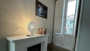 A modern living room with a fireplace, a decorative wall piece, and a view through a door. - Dimora Forgione B&B (Pietrelcina)