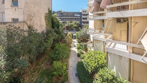 Un sendero estrecho entre edificios con balcones, rodeado de follaje y árboles.