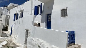 Eine Reihe weißer Gebäude mit blauen Türen und Fensterläden, schmale Wege dazwischen und ein klarer, blauer Himmel.