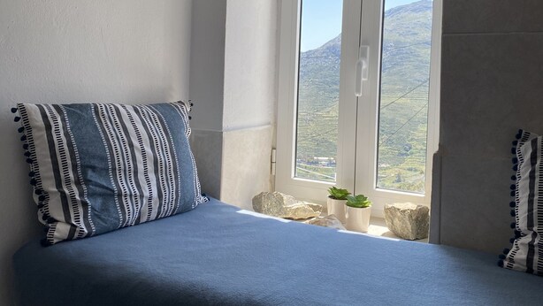 Ein Schlafzimmer mit einem Bett, einem Fenster mit Bergblick und einer Decke mit Schränken.