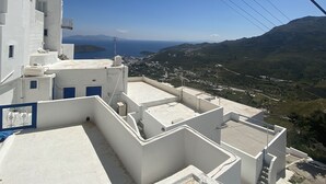 Ein weißes Gebäude mit Balkon, strahlend blauer Himmel und Blick auf eine hügelige Landschaft im Hintergrund.