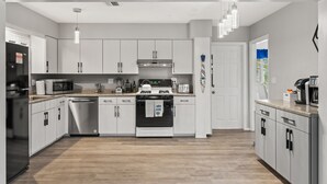 Een moderne keuken met witte kasten, roestvrijstalen apparatuur en een houten vloer.