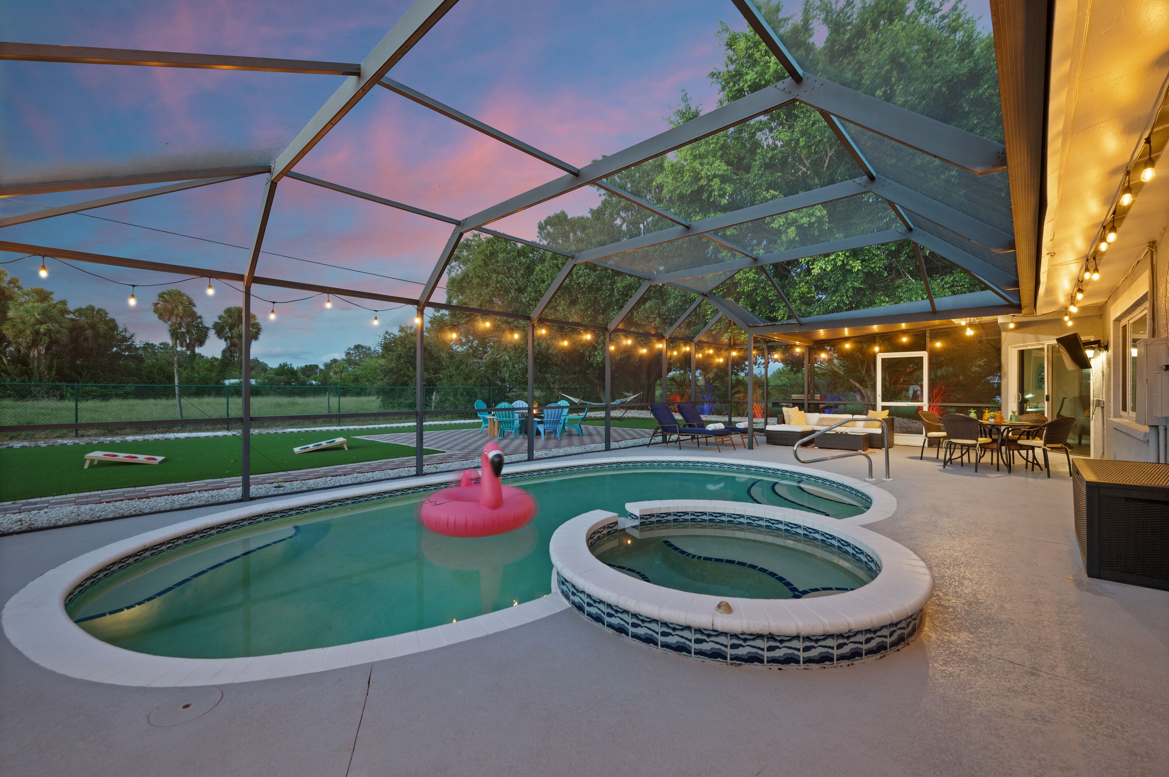 Una piscina esterna coperta con idromassaggio, lettini e luci decorative.