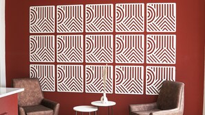 Una habitación con dos sillones de cuero, una mesita blanca y un panel decorativo en la pared.