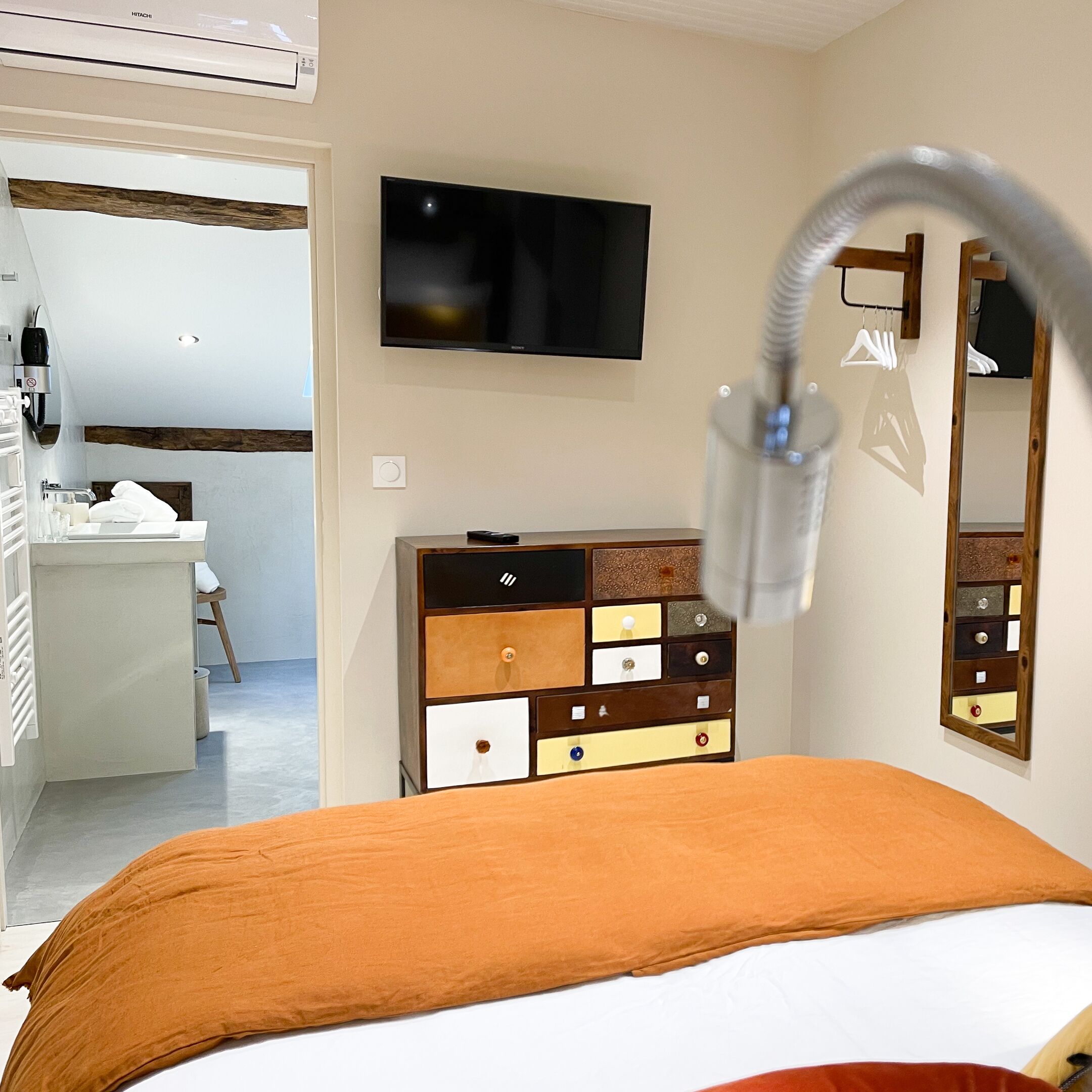 A hotel room with a bed, a dresser, a television, and a bathroom visible in the background.