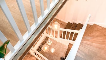 Una escalera de madera con barandillas blancas que baja a un nivel inferior.