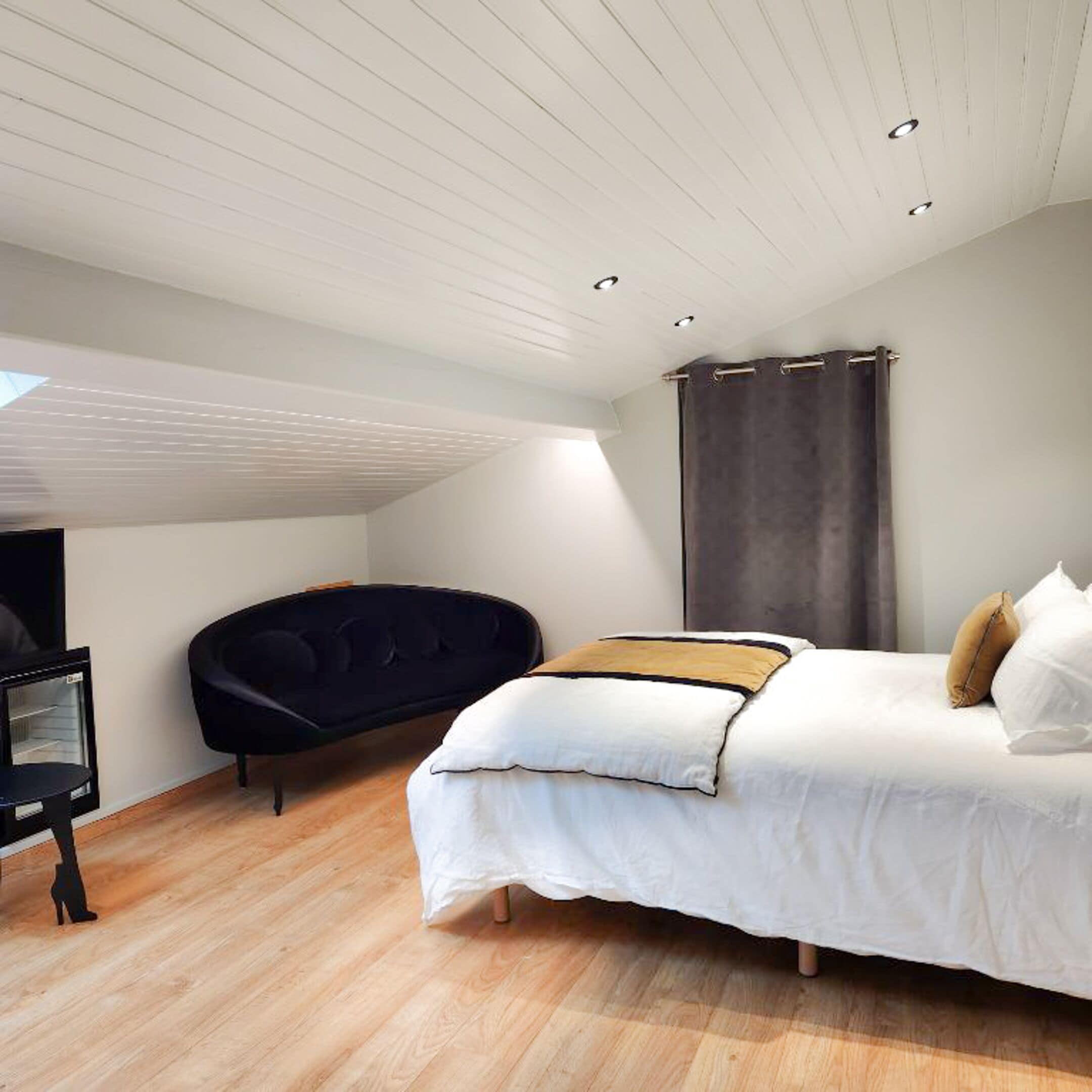 Een moderne slaapkamer met een bed, een donkere bank en een ingebouwde heater.