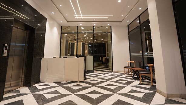 A modern lobby with a geometric patterned floor, a reception desk, and an elevator. - CIESTA TREEO (Mawal)