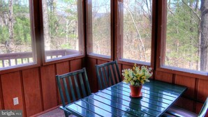 A wooden cabin with a glass-enclosed dining area, a table with chairs, and a potted plant.