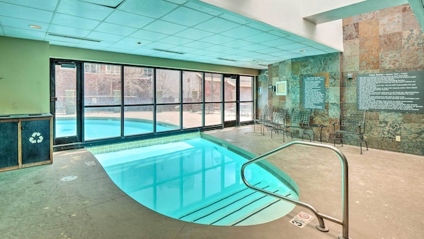 An indoor swimming pool with a clear view through large windows, a metal pool ladder, and a wall with informational signs. - Ski-In/Ski-Out Crested Butte Studio w/ Pool Access (Crested Butte)
