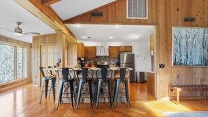 A spacious kitchen with wooden beams, a stone island, and modern appliances.