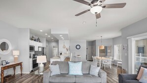 Un salon moderne avec un canapé gris, une table basse et un ventilateur de plafond.
