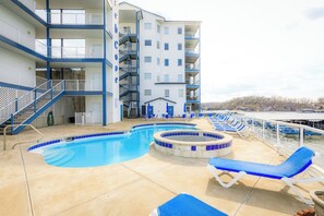 Un espace piscine avec des chaises longues, un escalier et un immeuble à plusieurs étages doté de balcons.