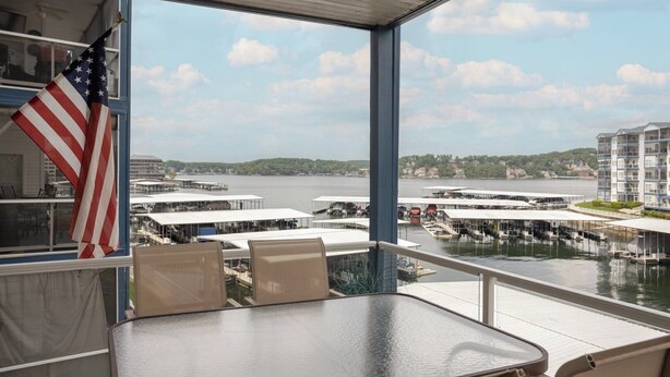 Un balcon donnant sur une marina, un drapeau américain et un espace repas avec une table et des chaises.
