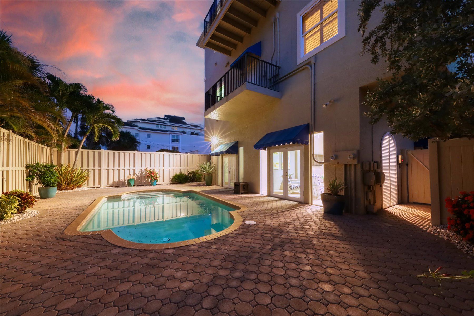 A pool area with a hexagonal tiled floor, a small pool, and a white fence.