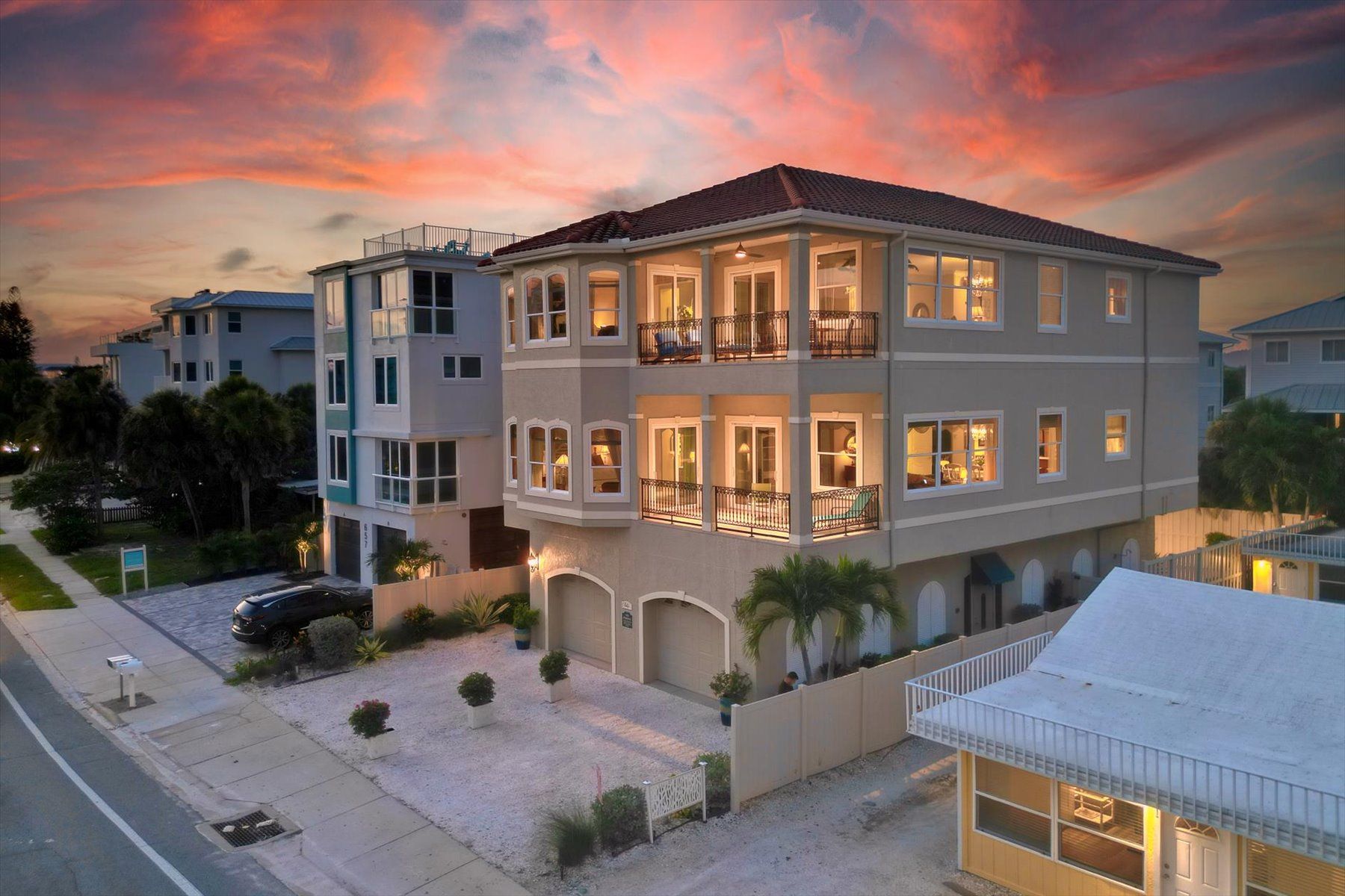 A multi-story residential building with a balcony on the second floor, a garage, and a driveway.