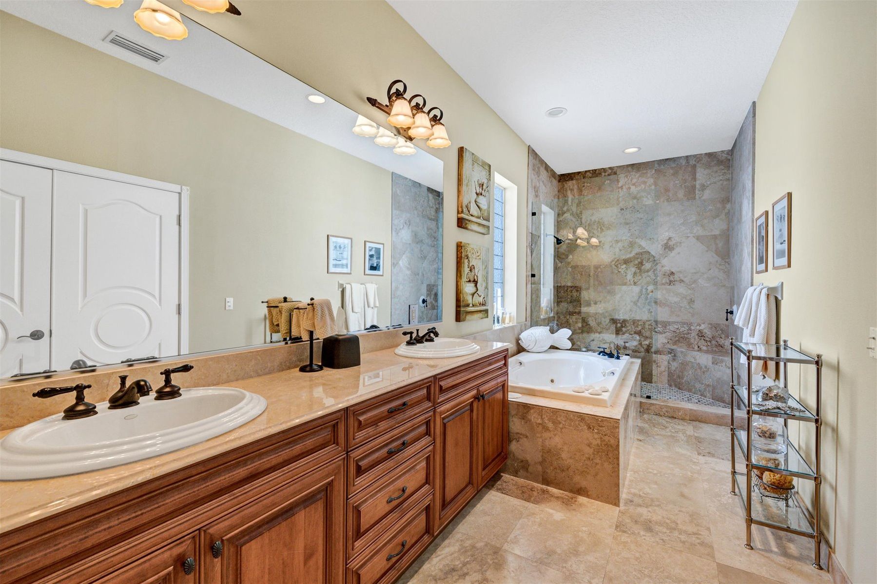 A spacious bathroom with a double sink vanity, a large mirror, a bathtub, and a shower area.