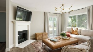 Un salon moderne avec une cheminée, un téléviseur, un canapé et une grande fenêtre avec des rideaux.