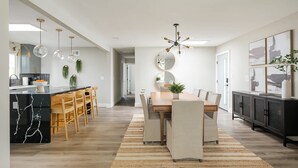 Een moderne keuken met een marmeren eiland, houten stoelen en een eettafel met vloerkleed.