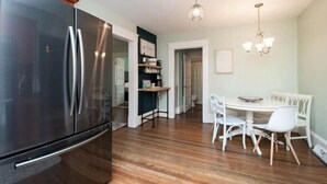 Eine Küche mit einem großen, edlen Kühlschrank aus Edelstahl, einem Esstisch mit weißen Stühlen und einer Kristallleuchter.