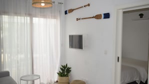 A room with a bed, a small table, a potted plant, and two wooden paddles on the wall. - Anacasa El Patio Denia PB1117 (Denia)