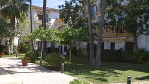 A courtyard with a paved walkway, potted plants, and a building with balconies. - Anacasa El Patio Denia PB1117 (Denia)